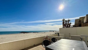A beach view with a patio area, lifebuoys, and a clear sky. - Dream house ground floor on the beach: prime location at the Mediterranean Sea (Palavas-les-Flots)