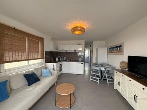 Eine moderne Wohnung mit Wohnzimmer, Essbereich, Küche und einem Balkon.