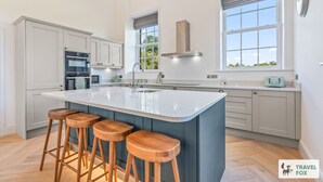 A modern kitchen with a large island, bar stools, and built-in appliances. - The Old Chapel - Lower Peaks (Alton Towers & Staffordshire Villages)