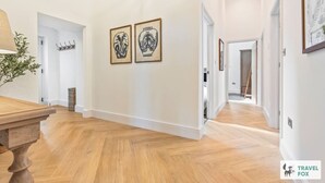 A hallway with wooden flooring, white walls, and two framed artworks. - The Old Chapel - Lower Peaks (Alton Towers & Staffordshire Villages)