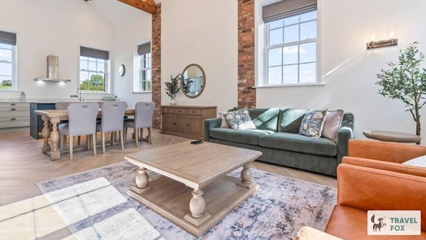 A spacious living area with a dining table, sofa, and a view of the kitchen. - The Old Chapel - Lower Peaks (Alton Towers & Staffordshire Villages)