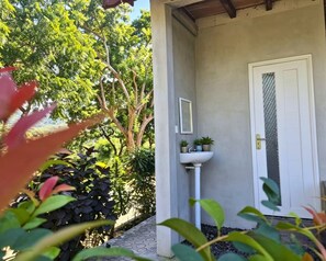 A building entrance with a white door, a small sink, and potted plants. - Sea Cliff Eco Nusa Penida (Penida Island)