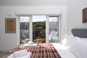 A hotel room with a bed, a balcony with a view, and a framed historical document on the wall. - River View - Cinema Room - Free Parking (Looe)
