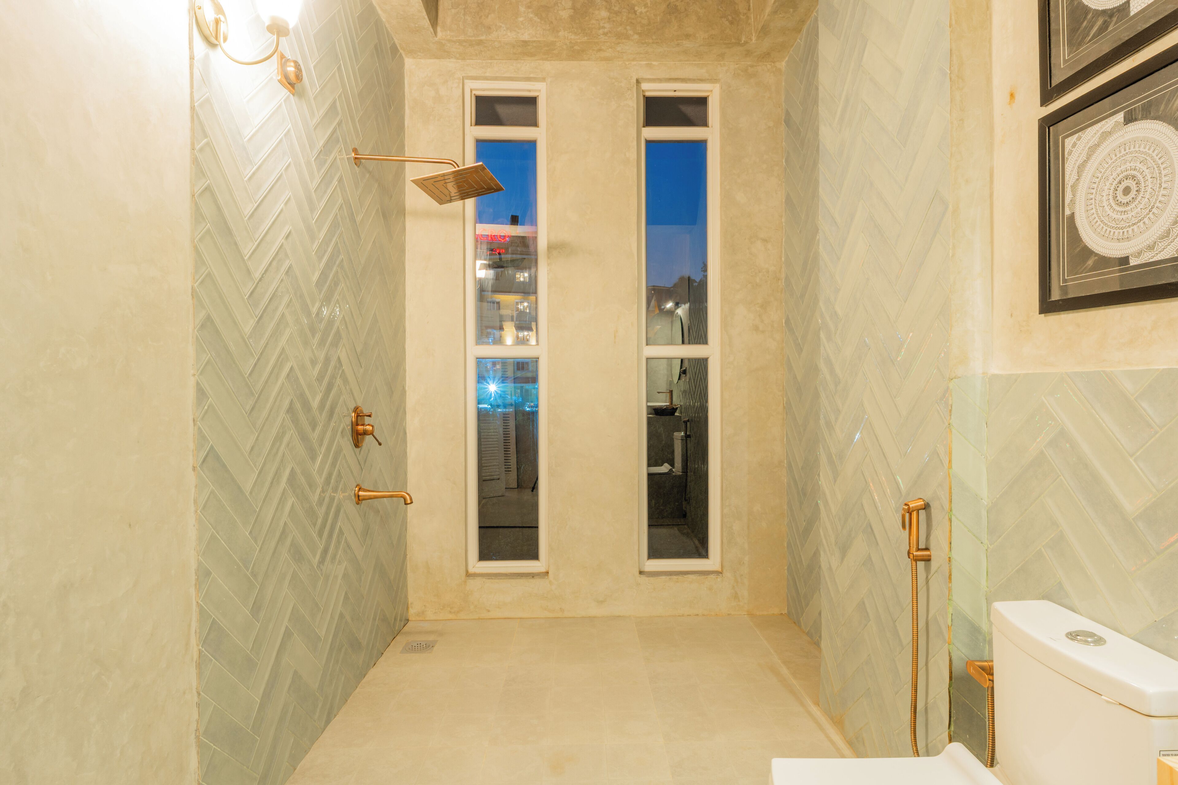 Un bany amb un mosaic de punt rombe, una dutxa amb plat de roba i un vàter amb aixeta bidet.