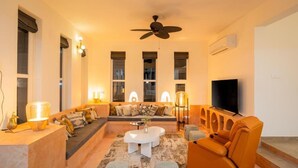 A modern living room with a sofa, coffee table, and orange armchair. - ELIVAAS Casa Mandala 4BHKVilla with pool (Candolim)