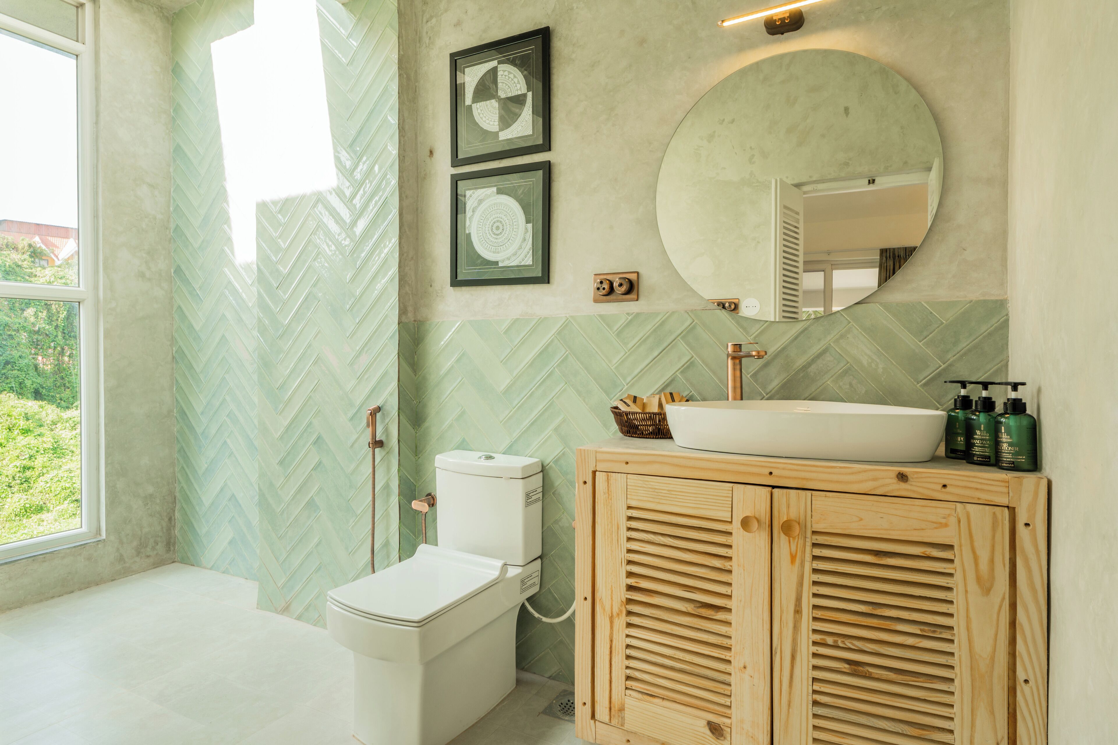 A bathroom with a herringbone-patterned wall, a white toilet, a wooden cabinet with a sink, and a large mirror.