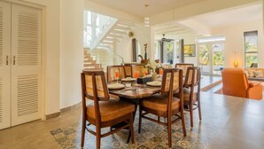 A spacious dining area with a high ceiling and a staircase leading to an upper level. - ELIVAAS Casa Mandala 4BHKVilla with pool (Candolim)