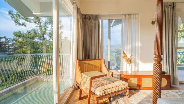 A balcony with a wicker chair, a wooden bed, and a view of the surrounding landscape. - ELIVAAS Casa Mandala 4BHKVilla with pool (Candolim)