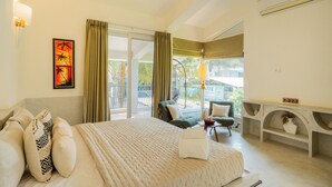 A hotel room with a large bed, a desk, and a view of the outdoors. - ELIVAAS Casa Mandala 4BHKVilla with pool (Candolim)