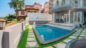 A residential property with a swimming pool, a balcony, and a well-maintained garden. - ELIVAAS Casa Mandala 4BHKVilla with pool (Candolim)