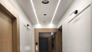 A hotel corridor with a wooden door on the left, a number '108' sign, and a room visible through the doorway. - hotel shiva inn (Ahmedabad)