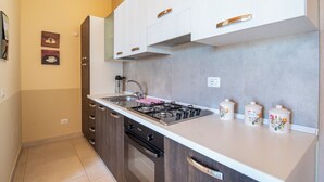 Una cucina moderna con piano cottura a gas, lavello in acciaio inossidabile e pensili in legno.
