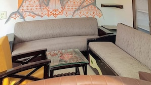 A living room with a sofa, a coffee table, and a ceiling fan. - Hotel Laxman Grand (Rishikesh)