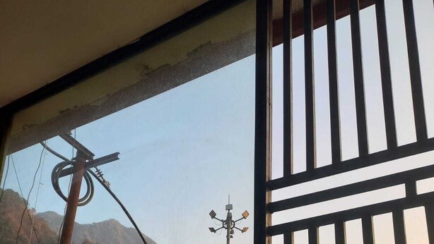 A view through a window with a metal grille, featuring a building with arched windows and a sign that reads "Hotel". - Hotel Laxman Grand (Rishikesh)