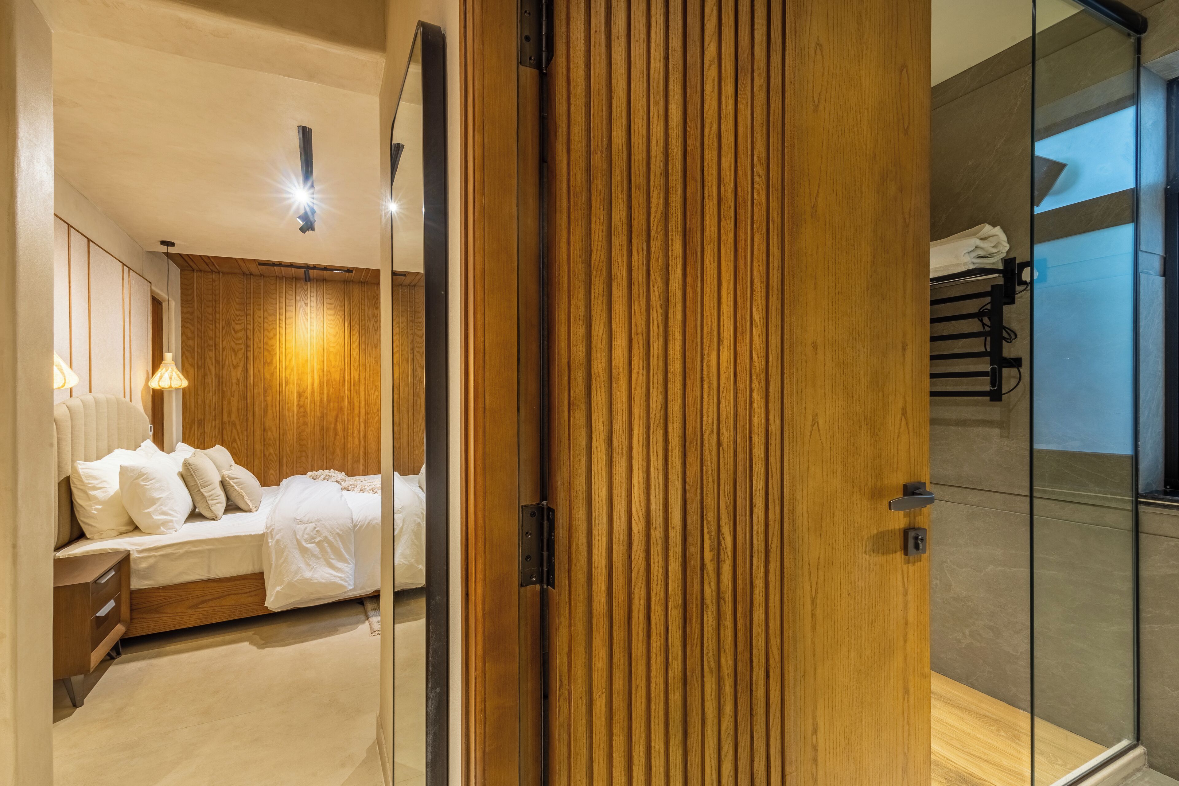 Un dormitorio moderno con un panel de madera en la pared, una cama con ropa de cama blanca y una mesita de noche.