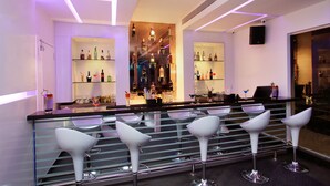 A bar area with modern bar stools, shelves with bottles, and a central bar counter. - Lavender Premier (Bengaluru)