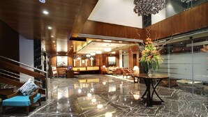 A lobby with a marble floor, wooden furniture, and a reception desk. - Lavender Premier (Bengaluru)