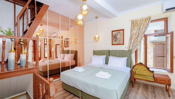 Un dormitorio con una cama grande, un banco de madera, una escalera y un espejo.