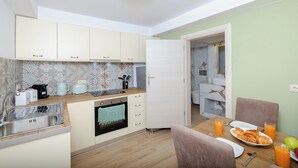 Cocina moderna con lavamanos, estufa y comedor con sillas y mesa lista para el desayuno.