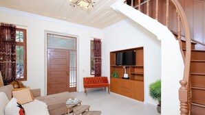 Una sala de estar con sofá, mesa de centro y televisor sobre un mueble de madera.