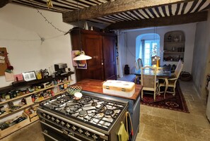 Une cuisine équipée d’une cuisinière à gaz, de meubles de rangement en bois et d’un coin repas avec une table et des chaises.