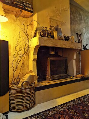 A cozy living room with a fireplace, a woven basket, and a patterned rug. - Romantic house in Provence with a terrace (Saignon)