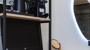 A modern kitchen with a wooden countertop, a coffee maker, and a computer setup.