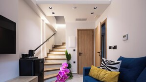 A modern living room with a blue sofa, a wooden coffee table, and a staircase leading to another room.
