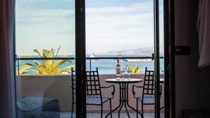 A balcony with a view of the sea, a bottle, and two chairs.
