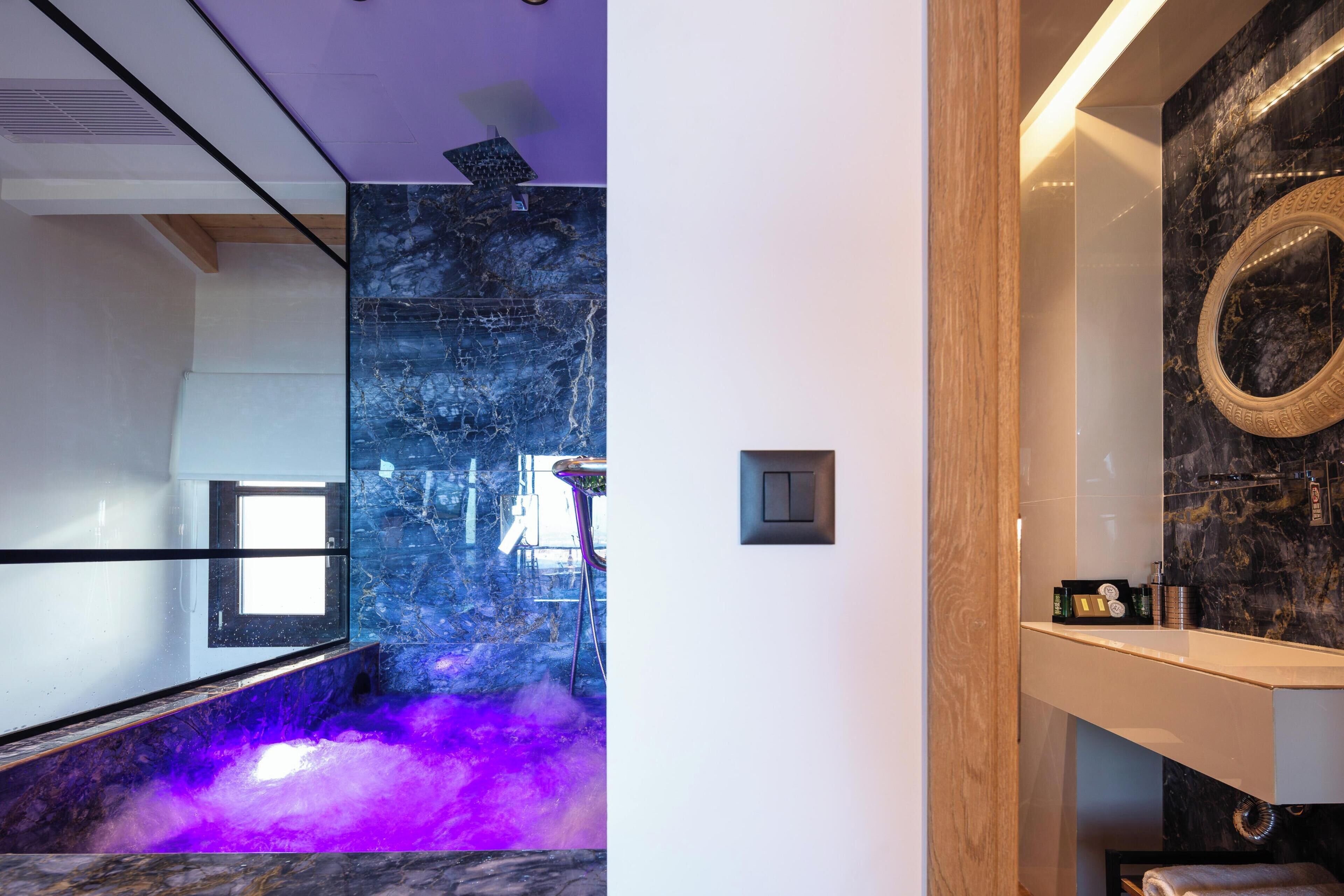 A modern bathroom with a marble wall, a mirror, and a shelf with toiletries.