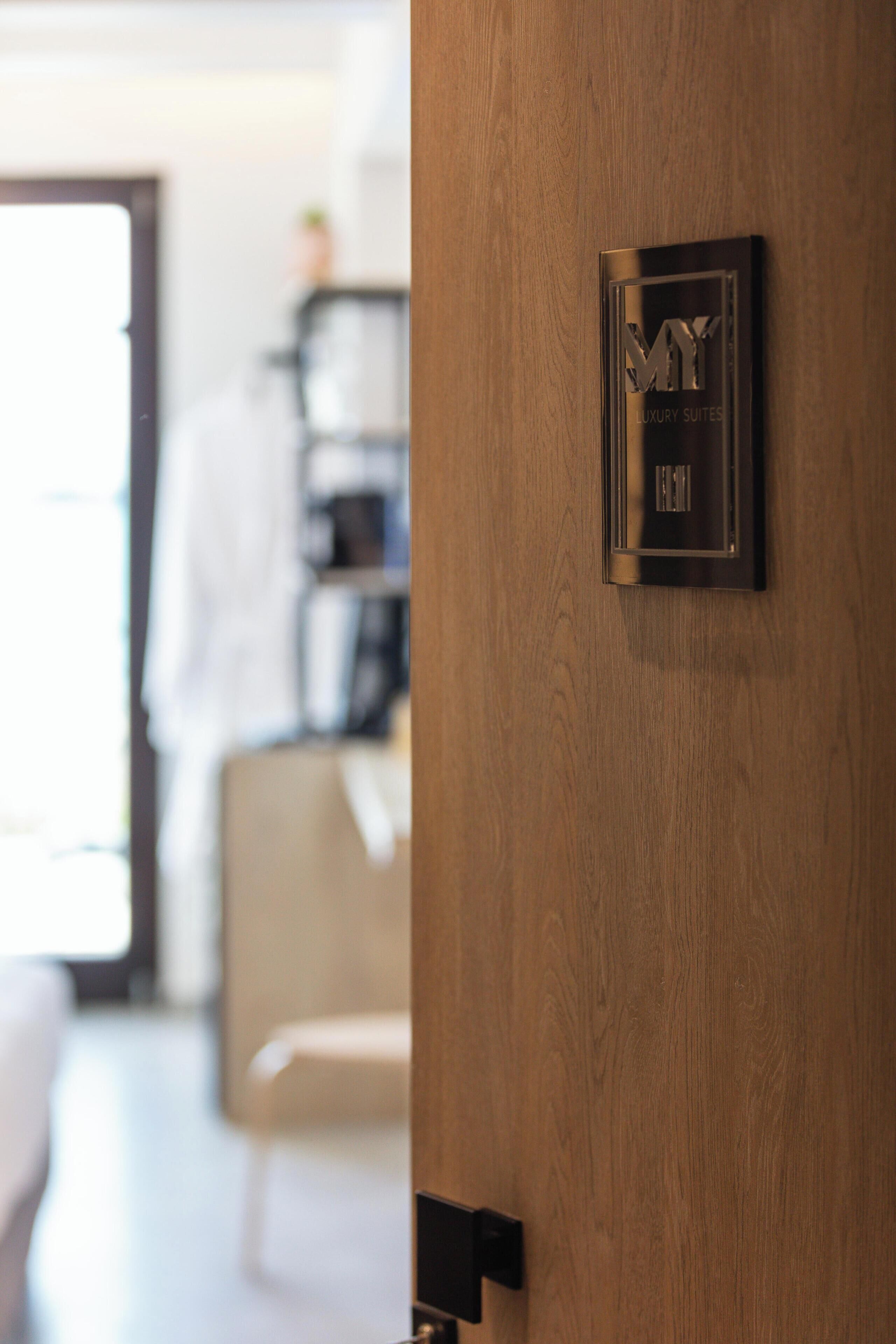Een houten deur met een bord waarop staat 'MY LUXURY SUITES'.