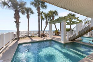 A pool area with a pergola, palm trees, and a view of the ocean. - New Day, Gulf-front Retreat with Private Pool (Panama City Beach)