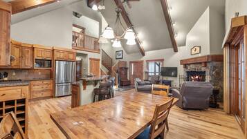 A spacious kitchen with wooden cabinets, a stainless steel refrigerator, and a large dining table.