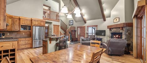 A spacious kitchen with wooden cabinets, a stainless steel refrigerator, and a large dining table.