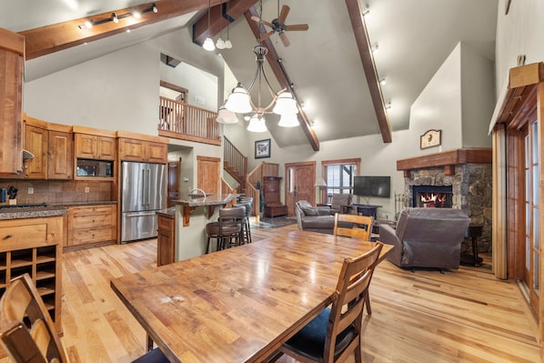 A spacious kitchen with wooden cabinets, a stainless steel refrigerator, and a large dining table.
