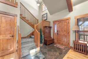 A wooden staircase with a handrail, a small Christmas tree, and a door with a window.