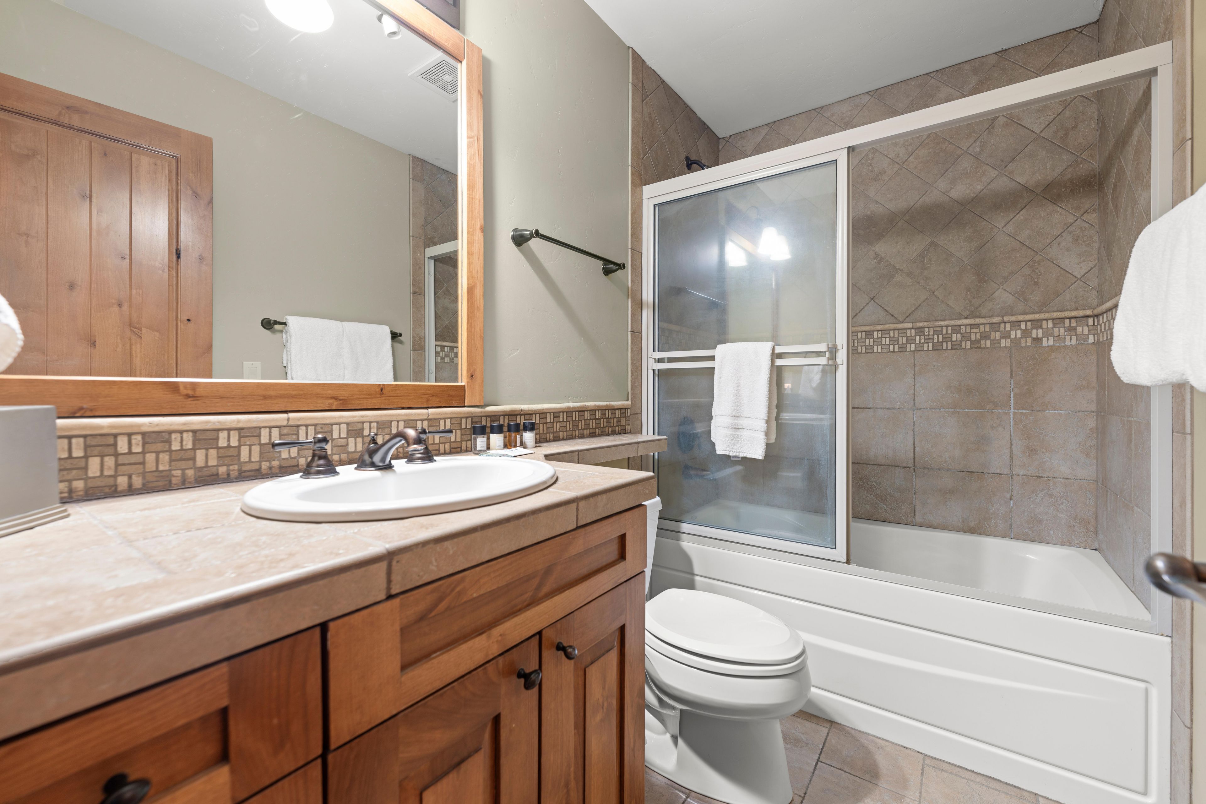A bathroom with two sinks, a toilet, a shower, and a large mirror.