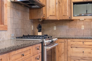 A kitchen with wooden cabinets, a stainless steel stove, and granite countertops.