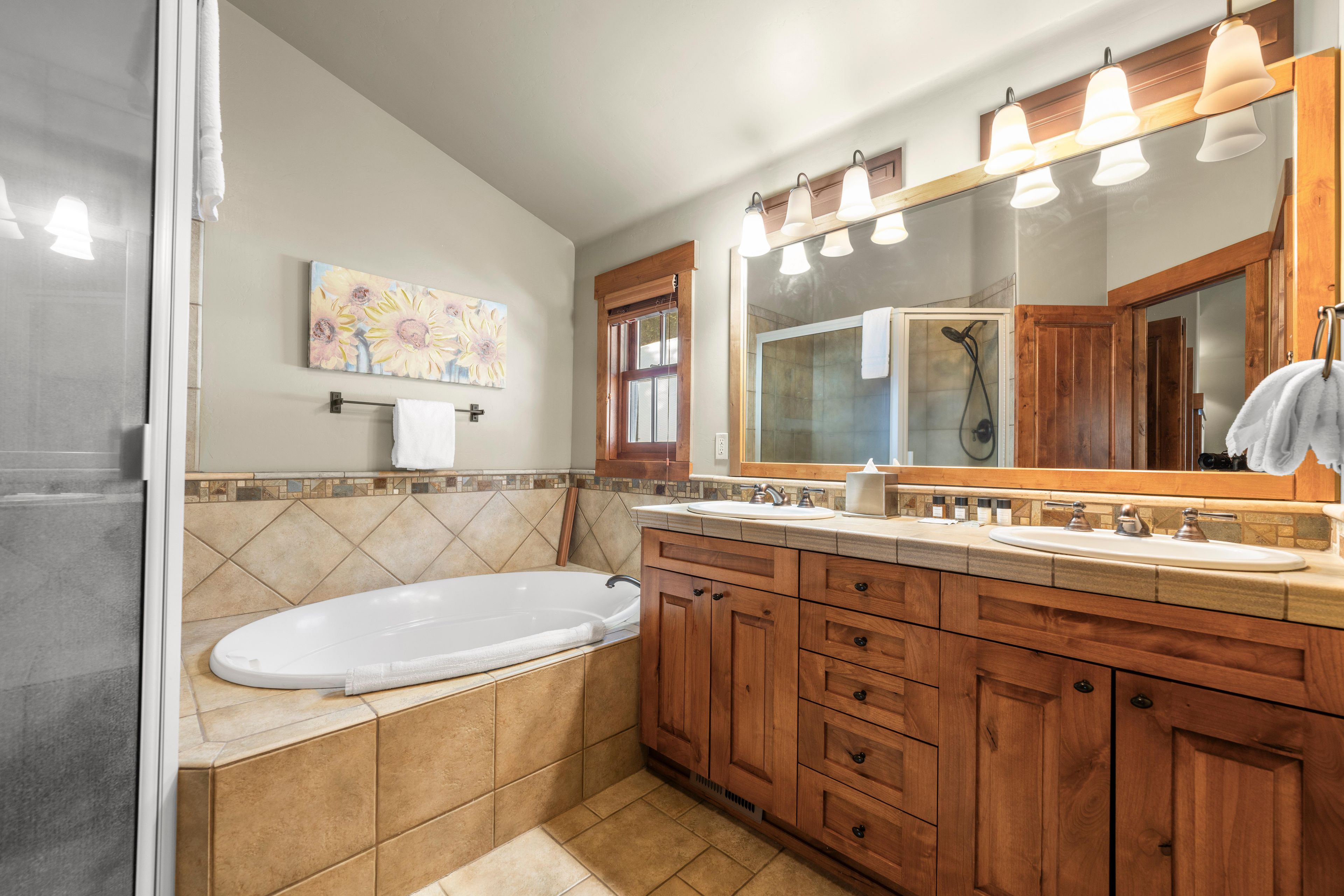 Ein Badezimmer mit einer Badewanne, einem Holzkosmetikschrank, einem großen Spiegel und einer Dusche.