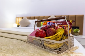 Ein Obstkorb auf einem Bett, im Hintergrund ein Kopfteil und Kissen.