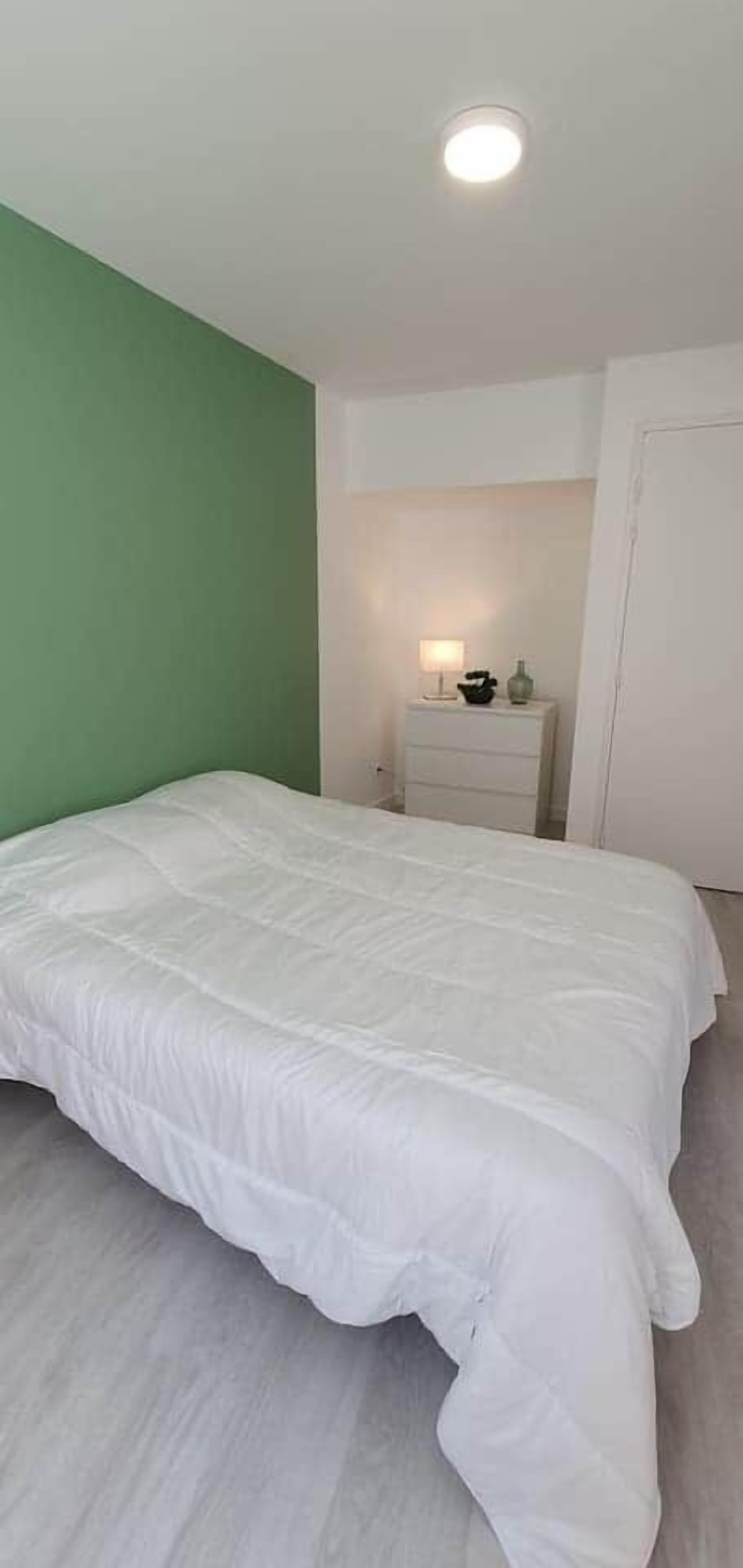 Une chambre à coucher avec un grand lit, une table de chevet avec une lampe et une porte.