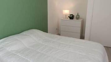 Une chambre à coucher avec un grand lit, une table de chevet avec une lampe et une porte.