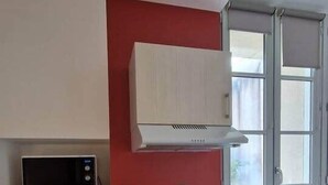 Eine kompakte Küche mit Mikrowelle, Kaffeemaschine und Backofen.