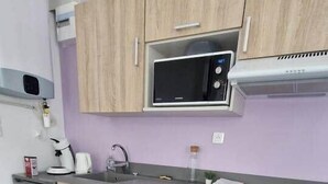 A compact kitchen with wooden cabinets, a stainless steel microwave, and a built-in oven.