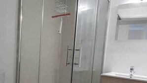 A bathroom with a glass-enclosed shower, a toilet, and a sink.
