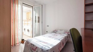 A bedroom with a bed, a green chair, a wardrobe, and a sliding glass door leading to a laundry area. - DETACHED HOUSE WITH GARDEN, FIVE MINUTES FROM THE BEACH. (Almeria)