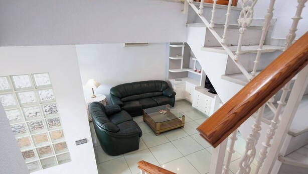 A modern living room with a black leather sofa, a glass coffee table, and white cabinetry. - DETACHED HOUSE WITH GARDEN, FIVE MINUTES FROM THE BEACH. (Almeria)