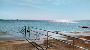 A coastal walkway with metal railings leading to the sea, a clear sky, and a distant ship. - Sea view apartment in Umag (Umag)