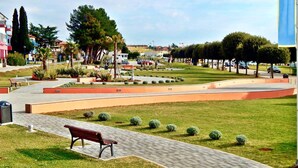 A park with a paved walkway, benches, and trimmed hedges. - Terrace flat 300 mt from beach (Zambratija)