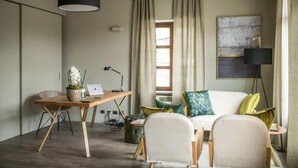 Una sala de estar moderna con un escritorio de madera, una computadora portátil, una planta en maceta y un sofá con cojines.